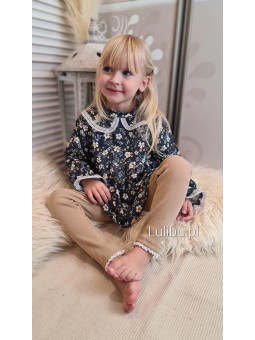 Dziewczynka w ciemnoniebieskiej tunice z kołnierzykiem w małe kwiatuszki w komplecie z beżowymi legginsami z bawełnianego prążka