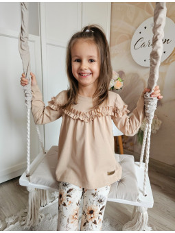 dziewczynka ubrana w gładka, beżowa tunika z falbanką i leginsy w kwiaty